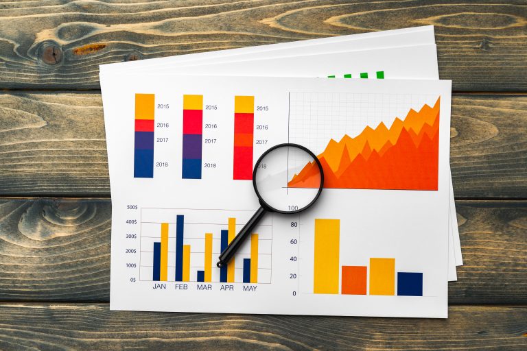 Business graphs and data displayed on paper with a magnifying glass