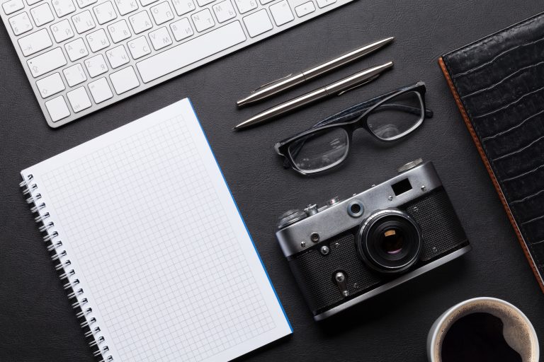 Office desk with camera, notepad and keyboard